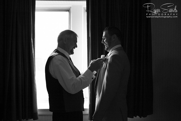 Grand Summit Hotel Wedding - Here you can see the groom standing in front of a large window having his flower pinned on his jacket on the morning of his wedding day.